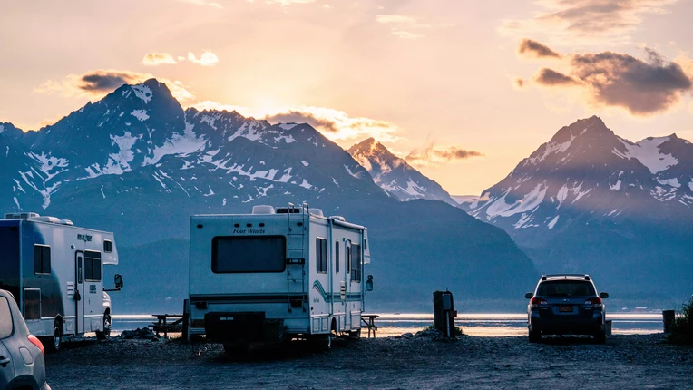 Camper vor einem See in den Bergen beim Sonnenuntergang.
